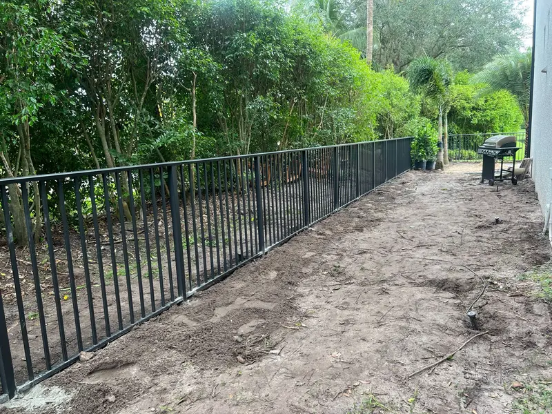 Black flat-top aluminum fence installed along a South Florida backyard in Broward County