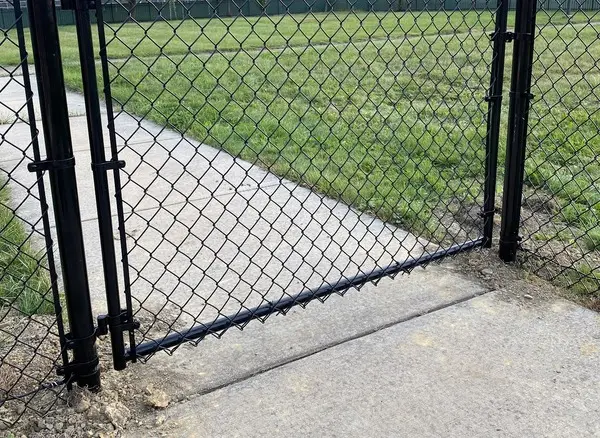 Black vinyl-coated chain link single swing gate over a walkway