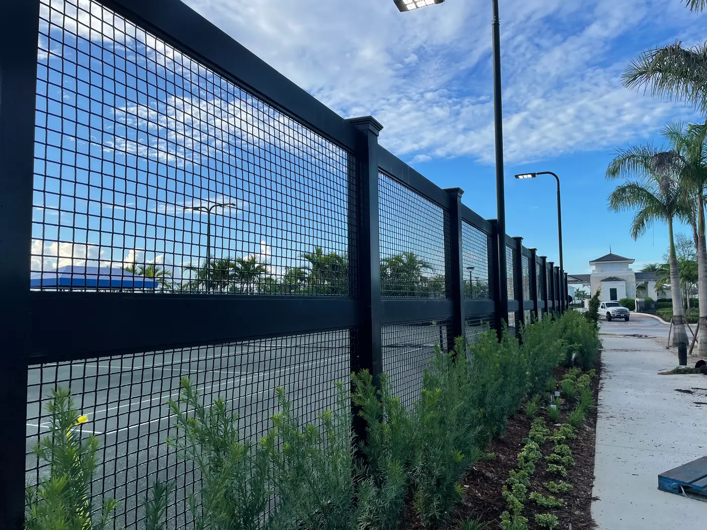 Black aluminum welded wire commercial fence lining an upscale South Florida property entrance