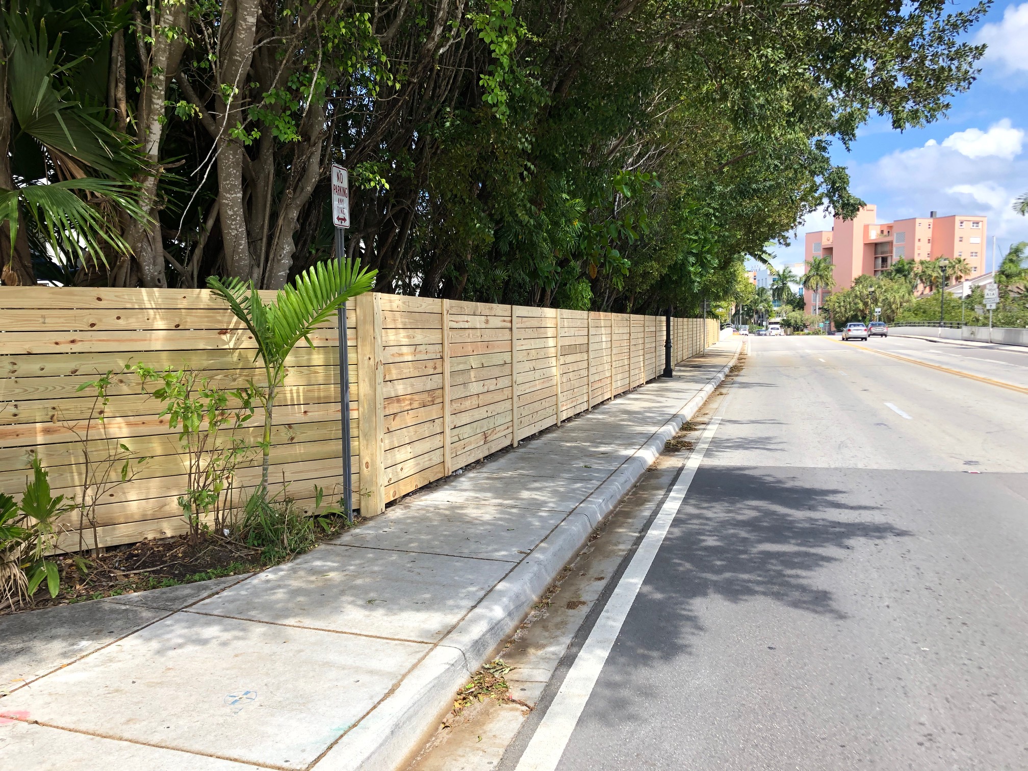 Horizontal wood privacy fence lining an HOA community streetscape in South Florida