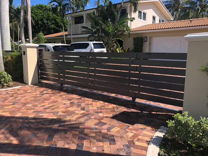 Custom-fabricated bronze aluminum horizontal-slat double-swing driveway gate by XL Fencing in South Florida