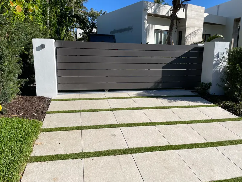 Charcoal aluminum horizontal-slat slide driveway gate at a modern South Florida home